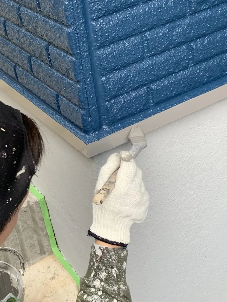 川崎市多摩区の外壁塗装工事現場で水切り板金の上塗り塗装作業です